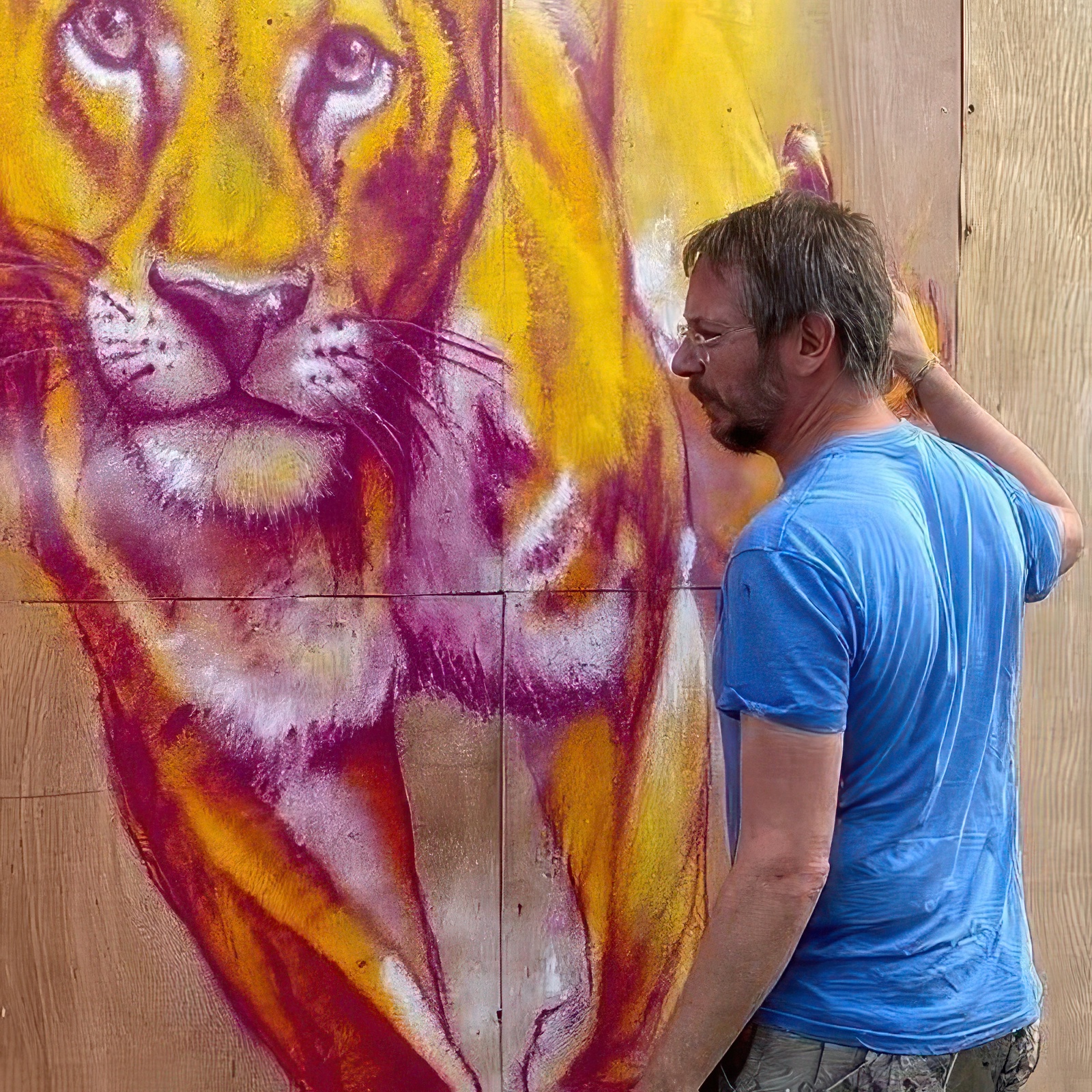 Mathieu, graffeur professionnel, peint une fresque murale représentant un lion